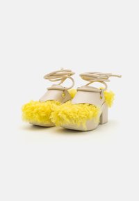 Beige plattform sko har gule faux fur detaljer på tåen, med ankelstropper og teksturert overflate for en sikker passform.