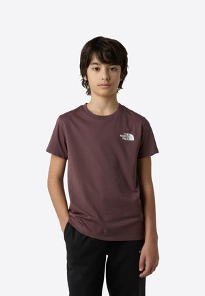 Körsbärsröd t-shirt med kort ärm i bomull, med en vit logotyp på bröstet. Parat med svarta byxor. Slät textur, klassisk passform.