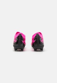 Scarpe da calcio nere e rosa con una finitura testurizzata, caratterizzate da una vestibilità aderente e un logo prominente. Progettate per una trazione ottimale sull'erba.