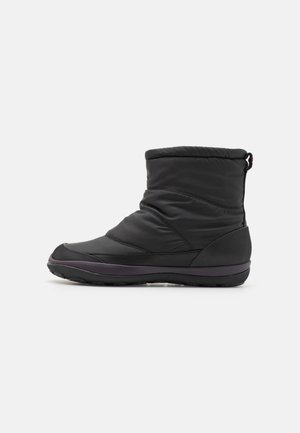 Black waterproof winter boot with quilted upper, rounded toe, textured rubber sole, and elastic cuff for secure fit. Features a pull tab.
