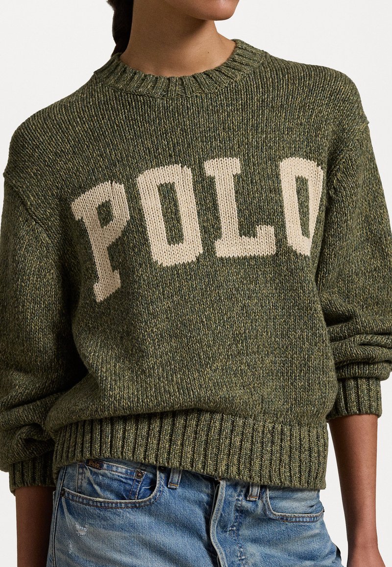 Olijfgroene gebreide trui met crèmekleurige "POLO" opdruk, ronde hals en geribbelde manchetten en zoom. Beschikt over een gemêleerd patroon en een relaxte pasvorm.