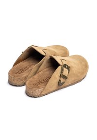 Zuecos beige de ante con hebilla ajustable, entresuela de corcho y suela exterior de goma texturizada. Diseño trasero abierto con un forro interior suave.