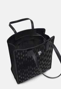 Czarna torba na ramię z teksturowanym geometrycznym wzorem, gładkimi skórzanymi paskami i zamykaną na zamek wewnętrzną kieszenią. Otwarty design zapewnia łatwy dostęp.
