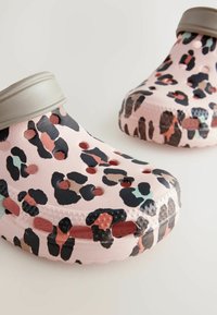 Ružové kroksy s leopardím vzorom v čiernej, zelenej a koralovej farbe. Majú ventilačné otvory a béžový pás okolo otvoru.