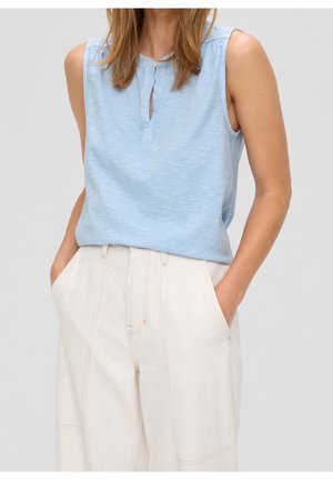 Haut sans manches bleu clair en tissu doux avec un décolleté en forme de goutte, associé à un pantalon beige taille haute à jambes larges avec des coutures visibles.