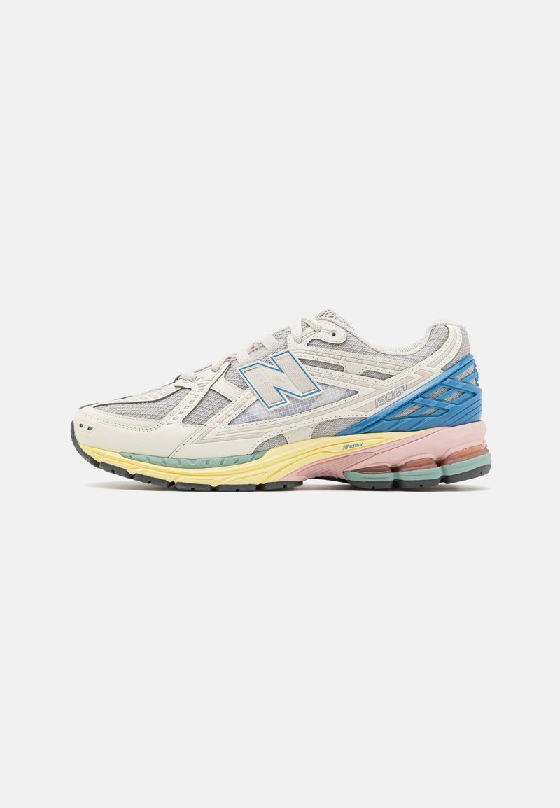 Zapatillas de correr New Balance con parte superior de malla y sintético, predominantemente blancas con acentos en azul, amarillo, rosa y verde. Suela texturada.