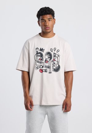Lichtbeige oversized t-shirt van katoen, met een gedurfde zwarte en rode grafische ontwerp met abstracte menselijke figuren en elementen.