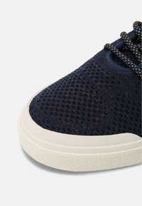 Marineblaue Mesh-Sneaker mit strukturiertem Obermaterial, cremefarbener Gummizwischensohle und kontrastierenden Schnürsenkeln. Hat eine abgerundete Zehenpartie und ein atmungsaktives Design.