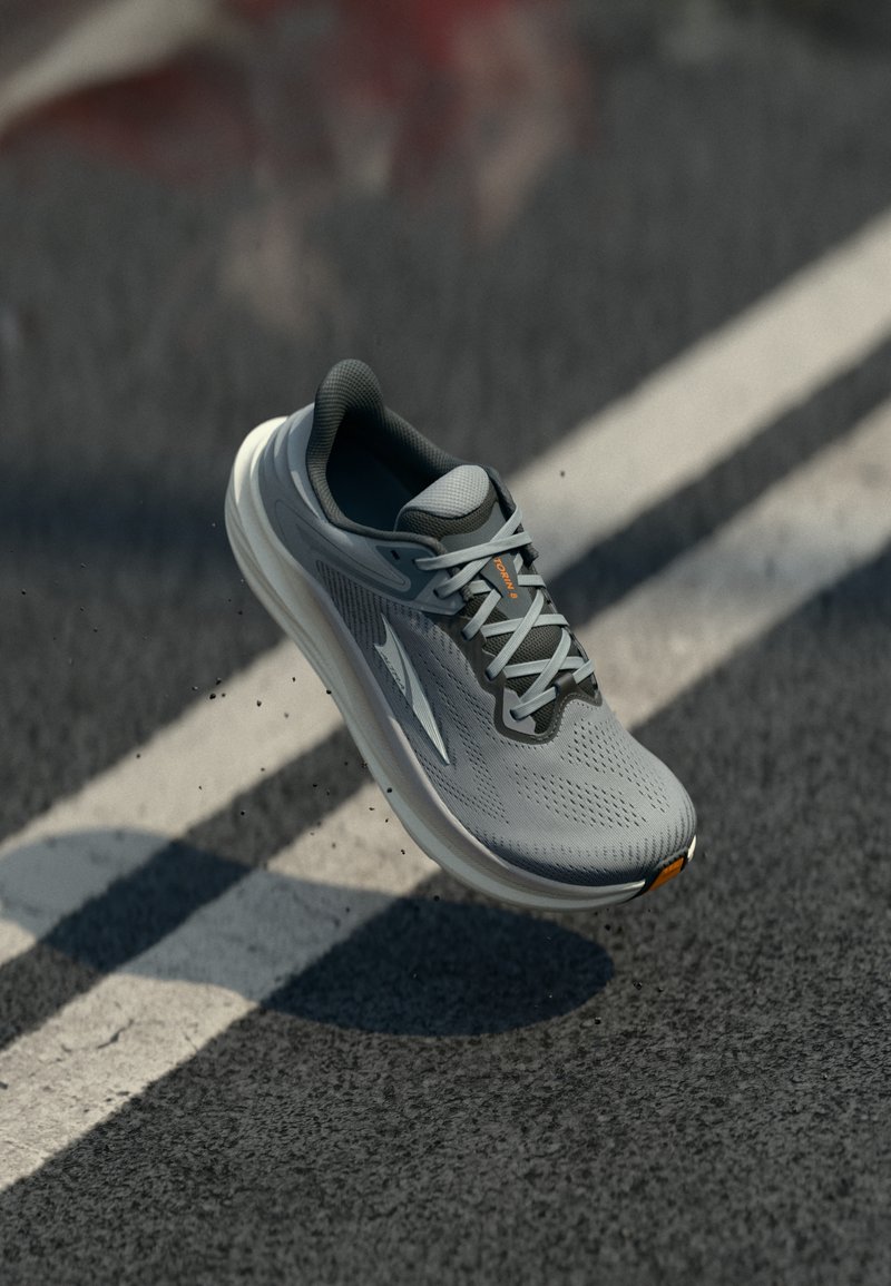 Light gray running shoe with mesh upper, padded collar, and white midsole. Features gray laces and orange branding on the side.