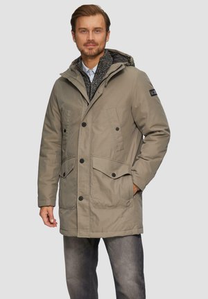 Parka beige avec capuche, fermeture à boutons sur le devant, deux grandes poches à rabat et une doublure intérieure à motifs. Fabriquée en matériau résistant à l'eau.
