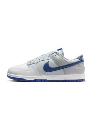 Lage witte sneaker met blauwe zool en blauw Nike Swoosh-logo, vanuit de zijkant weergegeven op een witte achtergrond.
