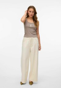 Lichtbeige tanktop met een zeepaardje grafiek, gecombineerd met losse, crème kleurige broek. Vriendelijke texturen en casual ontwerp, geschikt voor ontspannen dragen.