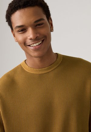 Sudadera marrón de textura acanalada con cuello redondo, que presenta un sutil patrón horizontal y un ajuste suave y relajado.