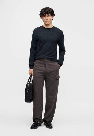 Μπλε πουκάμισο μακρυμάνικο με υφή, σκούρο καφέ παντελόνι φαρδύ με πλαϊνή τσέπη, μαύρη τσάντα με χερούλια και μαύρα παπούτσια. Απλός μοντέρνος σχεδιασμός.