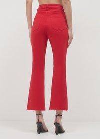 Rote Schlagjeans aus Denim, hoch tailliertes Design, mit Gesäßtaschen, rohem Saum und schmal an den Hüften sitzend mit ausgestelltem Beinabschluss.