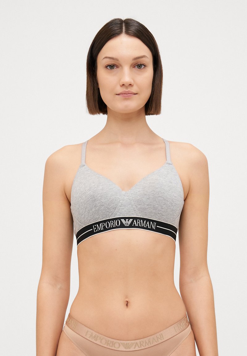 Grey cotton bralette with a V-neck and thin straps. Features a black waistband with "Emporio Armani" logo. Simple design, comfortable fit.