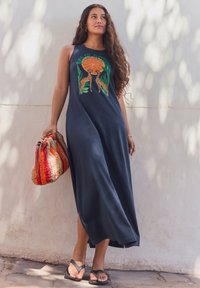 Tumesinine maxi kleit, millel on kaelkirjaku ja päikese kujutis ning külgede pikendused. Komplekti kuulub mitmevärviline kootud kott. Jalal on mustad varbavahed.