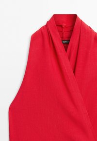 Red sleeveless wrap top with a V-neck collar and a visible brand label inside the neckline against a white background.