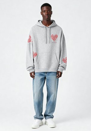 Grau, Kapuzenpullover mit roten Herzgrafiken auf den Ärmeln und der Brust, aus einem Baumwollmix gefertigt, kombiniert mit weit geschnittenen hellblauen Jeans.