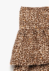 Leopardmønstret peplum-nederdel lavet af blødt, struktureret stof; har en tætsiddende talje og lagdelt flæse i kanten.