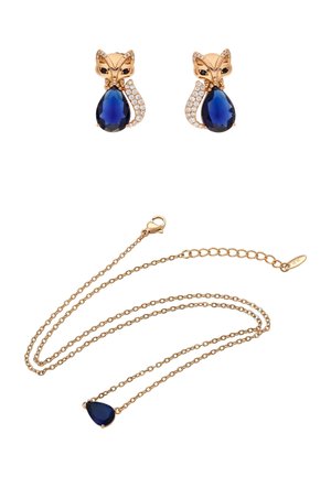Cercei aurii în formă de vulpe, cu pietre albastre în formă de lacrimă și cristale transparente, asortați cu un colier auriu cu pandantiv albastru în formă de lacrimă.
