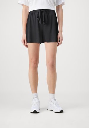 Shorts de sport noirs en tissu doux, dotés d'une taille élastique avec un cordon de serrage noué. Conçus pour le confort et le mouvement.