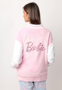 Chaqueta de forro polar rosa con mangas blancas, que presenta un logo de "Barbie" brillante en la parte posterior. Textura suave, cuello deportivo.