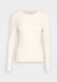 Top lungo a maniche con coste, di colore crema, con scollatura a girocollo, realizzato in tessuto morbido, caratterizzato da una silhouette aderente e una costruzione senza cuciture.
