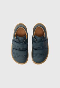 Παπούτσια από δέρμα σε ναυτικό μπλε με υφή, διαθέτουν δύο λουριά βέλκρο και καφέ λαστιχένια σόλα. Στρογγυλεμένο σχήμα και μινιμαλιστικός σχεδιασμός.