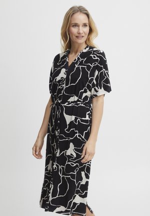 Schwarz-weißes, abstrakt gemustertes Kleid mit kurzen Ärmeln, einem V-Ausschnitt und einem Bindegürtel. Hat eine lockere Passform und seitliche Schlitze.