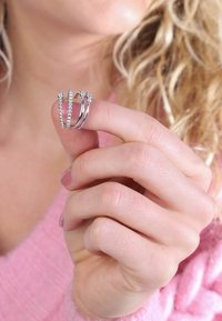 Drei silberne Ringe, die zwischen den Fingern gehalten werden. Ein Ring ist kunstvoll mit Perlen verziert, ein anderer hat kleine Steine, und der dritte ist ein glatter Band.