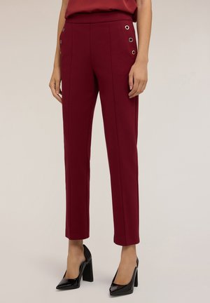 Pantaloni su misura bordeaux con una texture liscia, caratterizzati da dettagli in metallo dorato sui taschini anteriori e un taglio dritto.