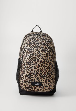 Mochila con estampado de leopardo, base beige, ribete negro y bolsillos laterales de malla. Cuenta con dos compartimentos con cremallera y un asa en la parte superior para llevar.