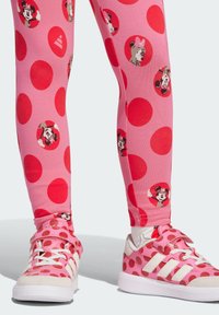 Pink leggings with large red polka dots and Minnie Mouse motifs. Paired with pink sneakers featuring red polka dots and white accents.