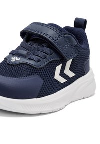 Mørkeblå mesh sneakers med en Velcro-strop, hvide detaljer og en tekstureret overdel. Har en polstret sål og en løkke for nem påtagning.