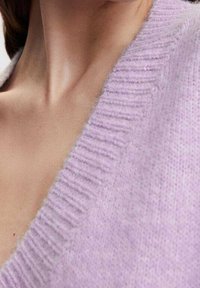 Cardigan en maille lavande avec un col en V profond, doté de bords côtelés et d'une texture douce. Le tissu semble moelleux et confortable.