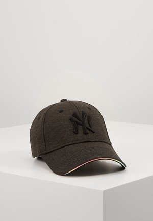 Casquette de baseball gris foncé avec logo NY noir et bordure arc-en-ciel discrète sur la visière incurvée, reposant sur une surface blanche.