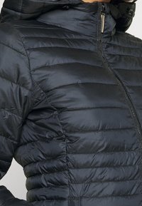 Giacca imbottita nera con cappuccio, caratterizzata da cuciture verticali trapuntate, chiusura frontale con zip e tessuto liscio e lucido.