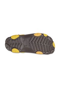 Shoe sole with a brown rubber base and yellow accents, featuring a textured tread pattern for grip and durability.