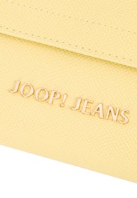 Rumena vegan usnjena denarnica z teksturirano površino; na sprednji strani ima zlato-tono logo "JOOP! JEANS" za subtilen poudarek.