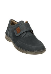 Grauer Lederschuh mit einem Klettverschluss, runder Zehenpartie, kontrastierenden braunen Akzenten und einer gepolsterten Sohle für Komfort.