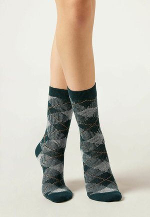 Chaussettes tricotées présentant un motif en losanges avec des accents vert foncé, gris et marron. Poignets côtelés et texture douce. Design de longueur crew.