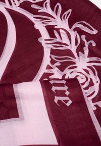 Burgunderfärgad och ljusrosa scarf med blommönster och texturerad yta; innehåller skrivstil och geometriska designelement.