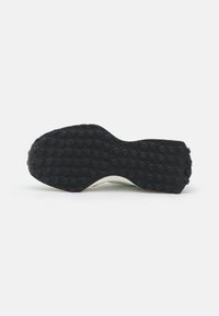 Semelle de chaussure avec une surface en caoutchouc noir texturé présentant des motifs de grip circulaires. Semelle intermédiaire blanche avec un léger arc et une forme courbée.