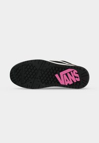 Черна подметка на обувка с грапав модел и голямо розово лого на Vans близо до петата на светъл едноцветен фон.