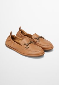 Tan leren instapschoenen met een ronde neus, plooidetail bij de opening en een metalen accent. Platte zool met een minimale profiel.