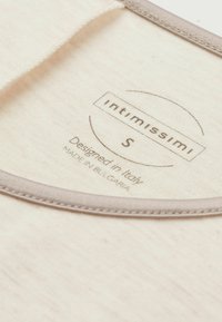 Vit tygmärke med grå kant, tryckt text inkluderar "Intimissimi," storlek "S," "Designad i Italien," och "Tillverkad i Bulgarien."