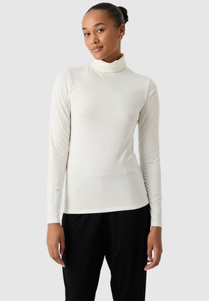 Top de manga larga con cuello alto tipo tortuga en color blanco roto, hecho de una tela suave y elástica, presenta un diseño ajustado con costuras planas.