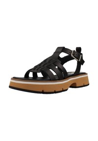 Sandalia de cuero tejido negro con tira ajustable en el tobillo y una suela gruesa bicolor en marrón y blanco. Presenta una suela de goma texturizada.