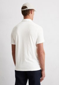 Korte mouw polo shirt in licht crèmekleurige katoen met een klassieke kraag, voorzien van een relaxte pasvorm en eenvoudige stiksels op de zoom en mouwen.